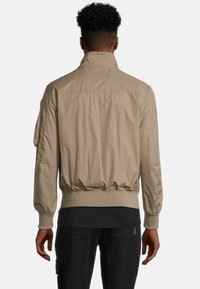 Lichtbeige bomberjack van nylonmateriaal, met een hoge kraag, ribgebreide manchetten en een elastische zoom. Gladde textuur zonder zichtbare patronen.