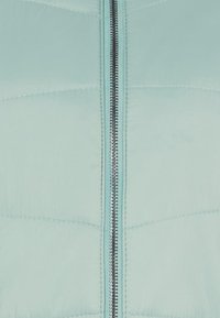 Giacca puffer azzurro chiaro con zip centrale e un motivo trapuntato sul tessuto. La texture appare liscia e leggermente lucida.