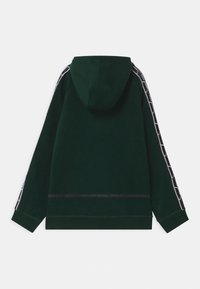 Felpa verde con tasca a marsupio, tessuto texture e cappuccio. Presenta strisce laterali bianche a contrasto con motivi geometrici.