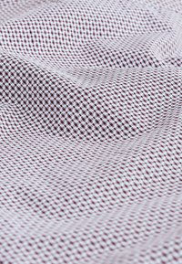 Tissu à carreaux rouges et blancs avec un tissage texturé. Les motifs sont de petits carrés uniformément espacés, créant un aspect en grille.