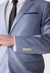 Hellblaues Blazer aus strukturiertem Stoff, mit einer einzelnen Brusttasche in marineblau und vier cremefarbenen Knöpfen an den Säumen.