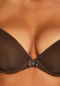 Brown push-up bra made of smooth fabric, featuring a delicate bow detail at the center and a sleek, molded cup design.