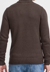 Braun gestrickter Pullover mit hohem Kragen, gerippten Ärmeln und Saum. Verfügt über eine strukturierte Oberfläche, eine figurbetonte Form und lange Ärmel.