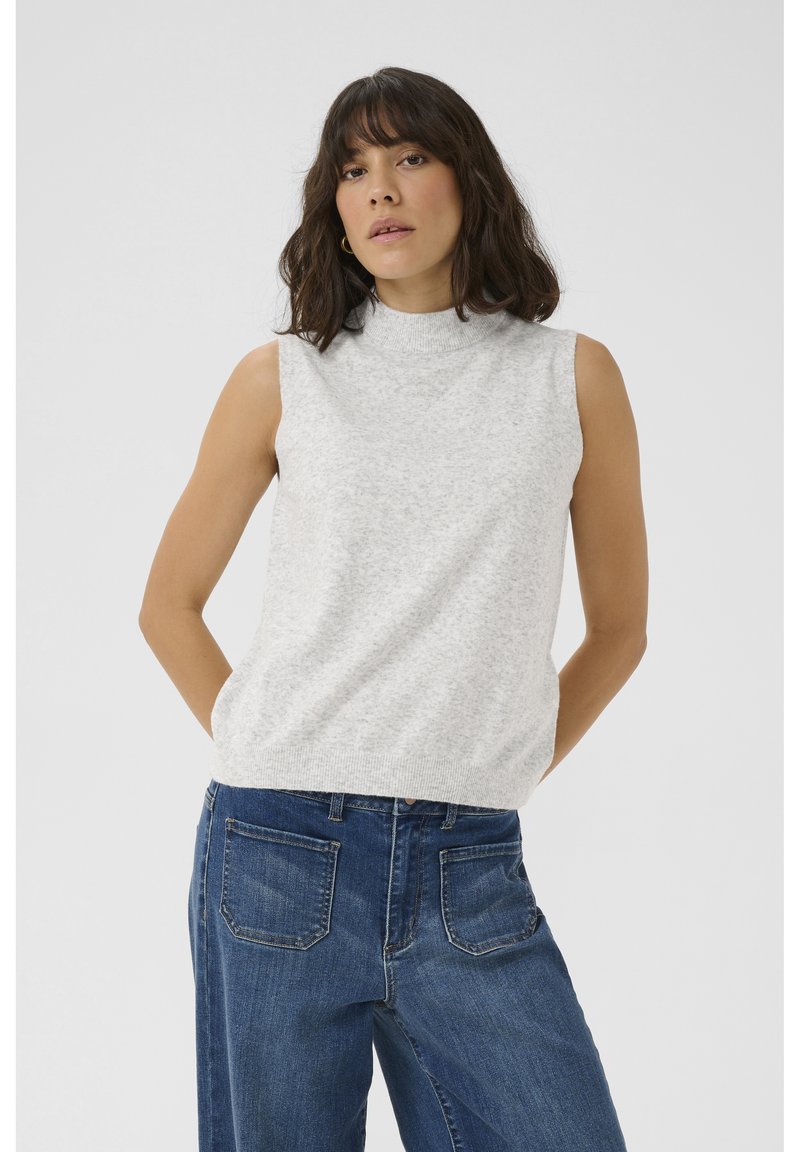 Lichtgrijze mouwloze gebreide top met een hoge halslijn en geribbelde zoom, gecombineerd met hooggetailleerde blauwe jeans met achterzakken.