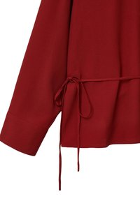 Blusa rossa con maniche lunghe, realizzata in tessuto liscio. Presenta un nastro in vita e un orlo dritto. Design semplice e minimalista.