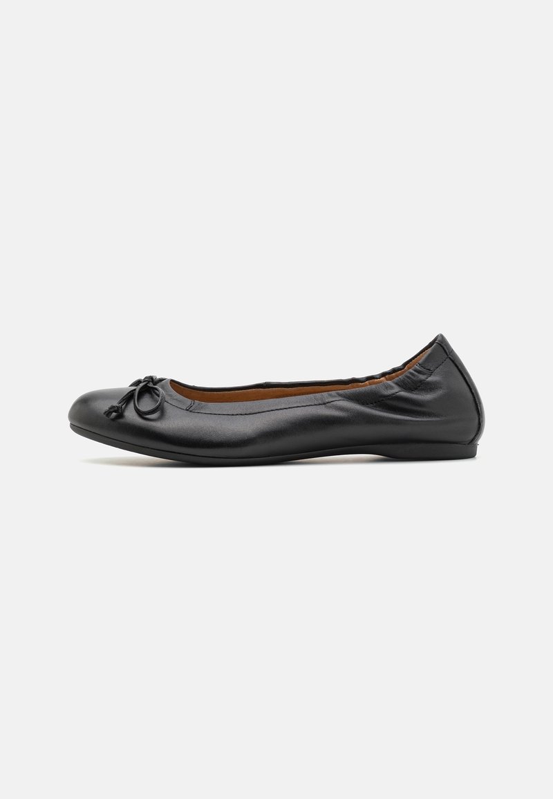 Ballet flat en cuir noir avec un bout rond, présentant un petit nœud sur le devant et une texture lisse. Design à profil bas.