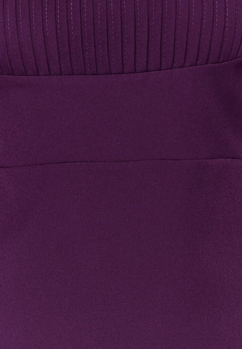 Robe violette présentant un corsage supérieur texturé et plissé, avec une section inférieure lisse et unie, mettant en avant une transition de couleur dans le tissu.