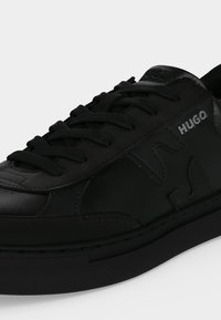 Μαύρο χαμηλό sneaker με κορδόνια, υφασμένες λεπτομέρειες και λογότυπο "HUGO" στο πλάι και στη γλώσσα.
