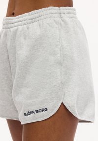 Κοντινό πλάνο ενός ατόμου που φοράει ανοιχτό γκρι σορτς Björn Borg με ελαστική μέση και λεπτομέρειες με σκίσιμο στο πλάι.