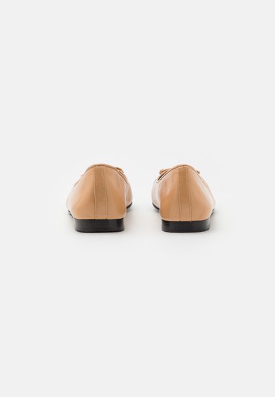 Ballerines en cuir beige à bout arrondi, avec peu de coutures et un petit talon noir. Texture lisse et design simple sans embellissements.