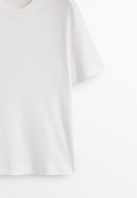 T-shirt bianca in cotone con scollatura rotonda e maniche corte. Texture liscia, taglio dritto e senza motivi o accenti visibili.