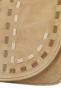 Borsa in suede beige con bordo cucito, motivi decorativi a intaglio e diverse sfumature di tessuto in forme e texture rettangolari.