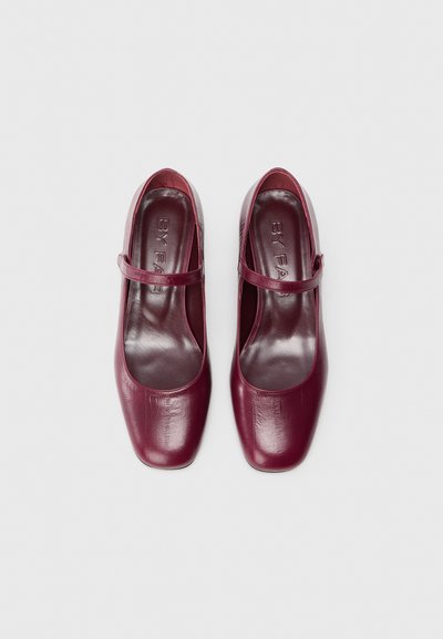 Scarpe Mary Jane in pelle bordeaux con punta quadrata, una sottile cinghia sulla parte superiore del piede e una finitura liscia e lucida.
