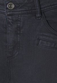 Mørkeblå denimjeans har en glat tekstur, synlige sømme, en metalknaplukning og en lappelomme-design.