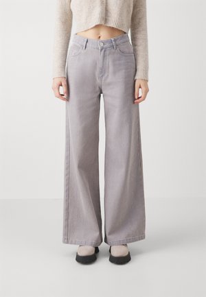 Lys grå vide bukser med høj talje, der har forlommer, bæltestropper og knaplukning. Glat denimtekstur.