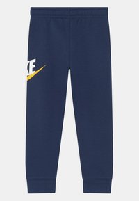 Mörkblå sweatpants med smal passform, elastiskt midjeband och gul och vit Nike-logotyp på vänster ben. Slätt bomullsmaterial.