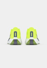 Neon yellow running shoes with mesh upper, navy accents, and a textured white sole. Features a pronounced heel and traction pattern.