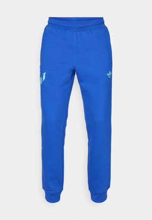 Blue sweatpants made of soft fabric, featuring a tapered design, elastic waistband, and pockets. Notable green accents and logo detail.