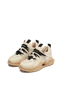 Beżowy sneaker z czarnymi sznurowadłami i elementami, teksturowana skórzana cholewka, masywna gumowa podeszwa oraz unikalny element designu po boku.