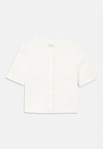 Cardigan blanc à manches courtes avec une texture côtelée, présentant un col rond, des fermetures à boutons et deux poches avant.