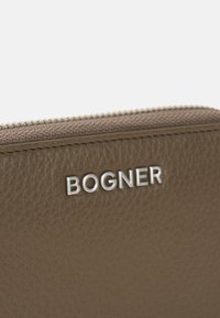 Funda de cuero texturizado marrón con un logo plateado "BOGNER" y una cremallera de contraste, con un ribete de tela suave en el borde superior.