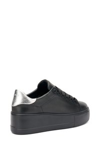 Baskets en cuir noir avec un accent argenté à l'arrière, bout rond, semelle épaisse noire et six œillets pour les lacets.