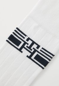 Chaussettes en coton blanc avec un motif géométrique bleu marine et un logo sur la partie centrale ; texture côtelée pour un confort et un ajustement accrus.