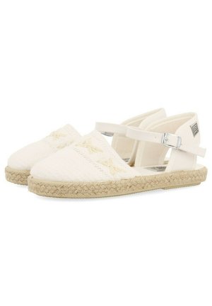 Espadrilles en toile blanche avec des détails en point de croix, une semelle en jute et des sangles de cheville ajustables. Design simple et plat avec des accents minimalistes.