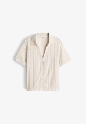 Korte mouwen beige vest met knopen, subtiele verticale strepen en een zachte kraag, plat gelegd op een witte achtergrond.