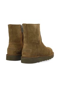 Botas de tobillo marrones de ante con cremalleras laterales y suelas gruesas oscuras, mostradas desde atrás y en una vista lateral ligeramente en ángulo.