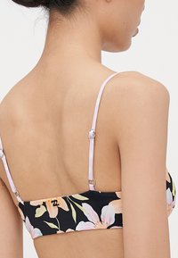 Blomsterbikinitopp med svart bakgrunn, prydet med pastellfargede blomster. Lyse lilla justerbare stropper med sølvfarge.