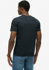 Zwart T-shirt met korte mouwen en ronde hals. Gemaakt van katoen met een gladde textuur. Gecombineerd met blauwe spijkerbroek, toont een aansluitende achterkant.