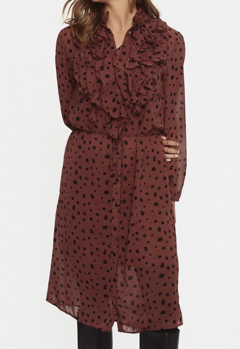 Brązowa przezroczysta sukienka w czarne kropki, z falbaniastym kołnierzem i przodem, z zapięciem na guziki oraz regulowanym paskiem w talii, z długimi rękawami.