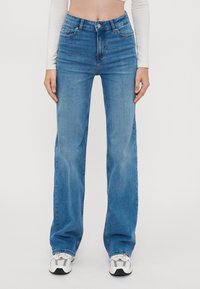 Hellblaue Denim-Jeans mit weitem Bein und hoher Taille, mit frontalen Taschen, Gürtelschlaufen und einem Knopfverschluss. Glatte Textur und klassisches Design.