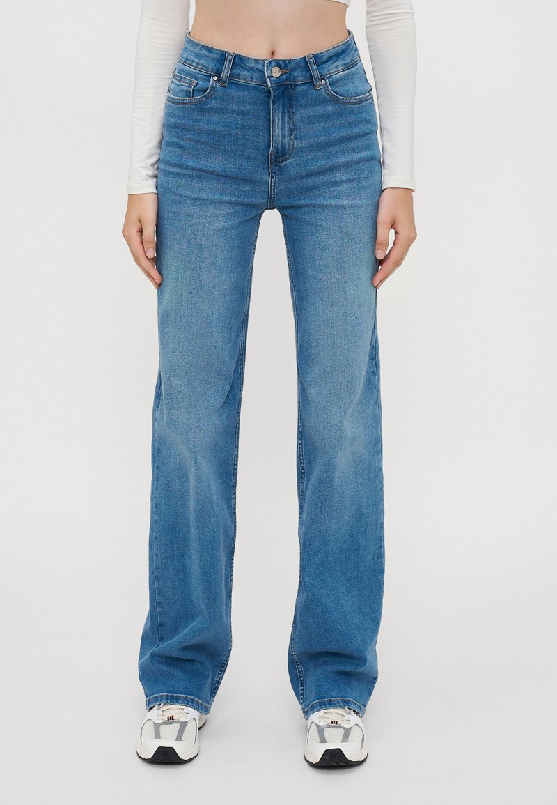 Hellblaue Denim-Jeans mit weitem Bein und hoher Taille, mit frontalen Taschen, Gürtelschlaufen und einem Knopfverschluss. Glatte Textur und klassisches Design.