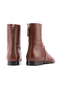 Braune Leder-Ankle-Boots mit glatter Textur, ausgestattet mit einem seitlichen Reißverschluss und einem niedrigen schwarzen Absatz. Sauberes Design mit minimalen Akzenten.