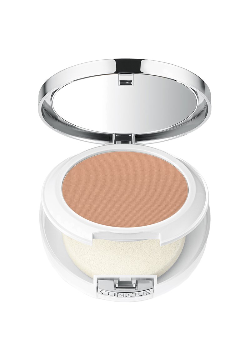 Poudre compacte dans un étui blanc avec un couvercle miroir. Contient une poudre beige et une éponge applicatrice blanche. Détail en métal argenté visible.