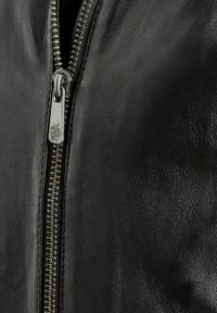 Schwarze Lederjacke mit einem Metallreißverschluss, glatter Textur und einer Nahaufnahme des Reißverschluss-Details auf dem Leder. 