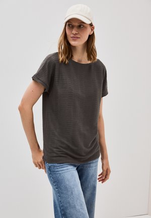 Grå stribet kortærmet T-shirt med en løs pasform, parret med lyseblå jeans og en hvid kasket. Glat tekstur og rund halsudskæring.