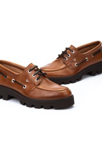 Chaussures en cuir marron à finition lisse, dotées de lacets noirs, d'œillets en métal et d'une semelle noire épaisse et texturée. Design à bout rond.