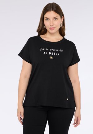 T-shirt nera in cotone con testo bianco che recita "Stai serena lo dici AL METEO" e una piccola grafica del sole, con maniche corte arrotolate e scollatura rotonda.