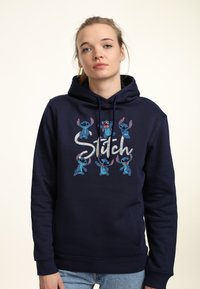 Felpa navy con cappuccio caratterizzata da una stampa grafica di personaggi Stitch blu con espressioni varie. Tessuto in cotone, cappuccio regolabile con cordino e tasca frontale.