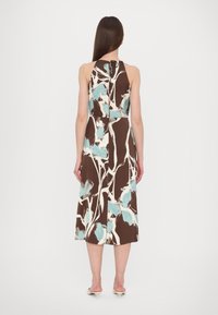 Robe midi florale marron avec des motifs bleu clair et blancs, de design à encolure halter et fermeture à nouer à l'arrière, présentant une silhouette fluide.
