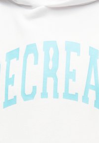 Λευκό ύφασμα με μεγάλα, ανοιχτό μπλε γράμματα σε μπλοκ που δείχνουν μερικώς τη λέξη "ICE CREAM" σε καμπυλωτή διάταξη.