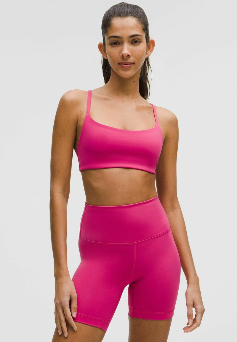 Sutien sport cu padding, de culoare roz, cu bretele subțiri, asortat cu șorturi roz cu talie înaltă. Textură netedă și design ajustat.