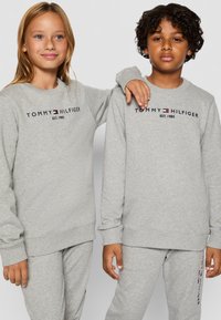 Szürke pulóver szett puha anyagból, kerek nyakú és bordázott mandzsettával. Az elülső részén "TOMMY HILFIGER" logóval.