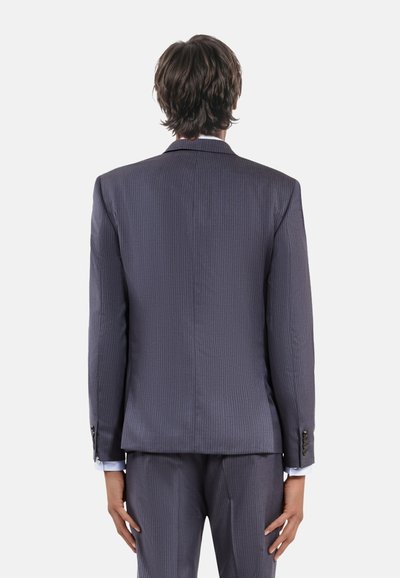 Chaqueta de traje a rayas gris oscuro, con una abertura trasera, tela texturizada, con pantalones a juego y puños de camisa azul claro visibles.