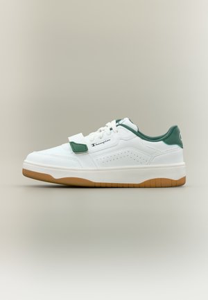 Baskets blanches avec accents verts, en cuir et matériau synthétique, fermeture par lacets et Velcro, côtés perforés, et semelle extérieure en caoutchouc naturel.