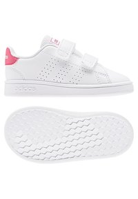 Baskets synthétiques blanches avec des accents roses, dotées d'une fermeture à double Velcro, de bandes latérales perforées et d'une semelle extérieure texturée hexagonale.