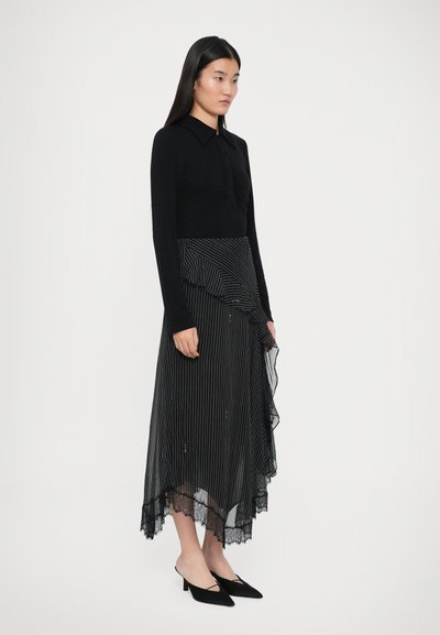 Top de manga larga negro con cuello, combinado con una falda plisada a rayas en blanco y negro que presenta un dobladillo de encaje y un diseño fluido. Zapatos de tacón negros.